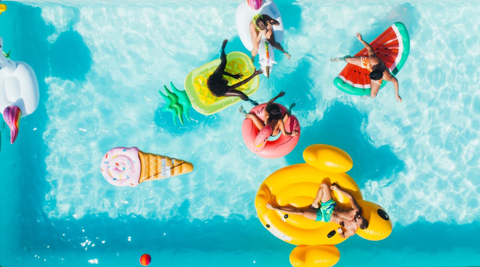 Bunte Pool-Floats mit Personen im Wasser