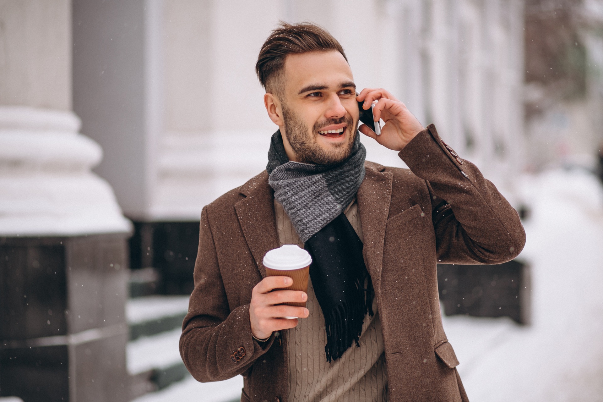 Geschaeftsmann telefoniert draussen im Winter mit Kaffee | Heizanhänger